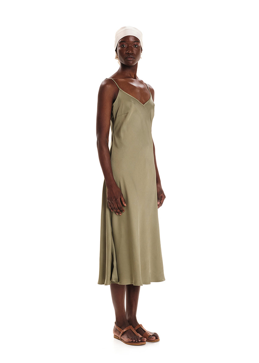 A model wearing a midi length sleeveless green dress with adjustable shoulder straps.
