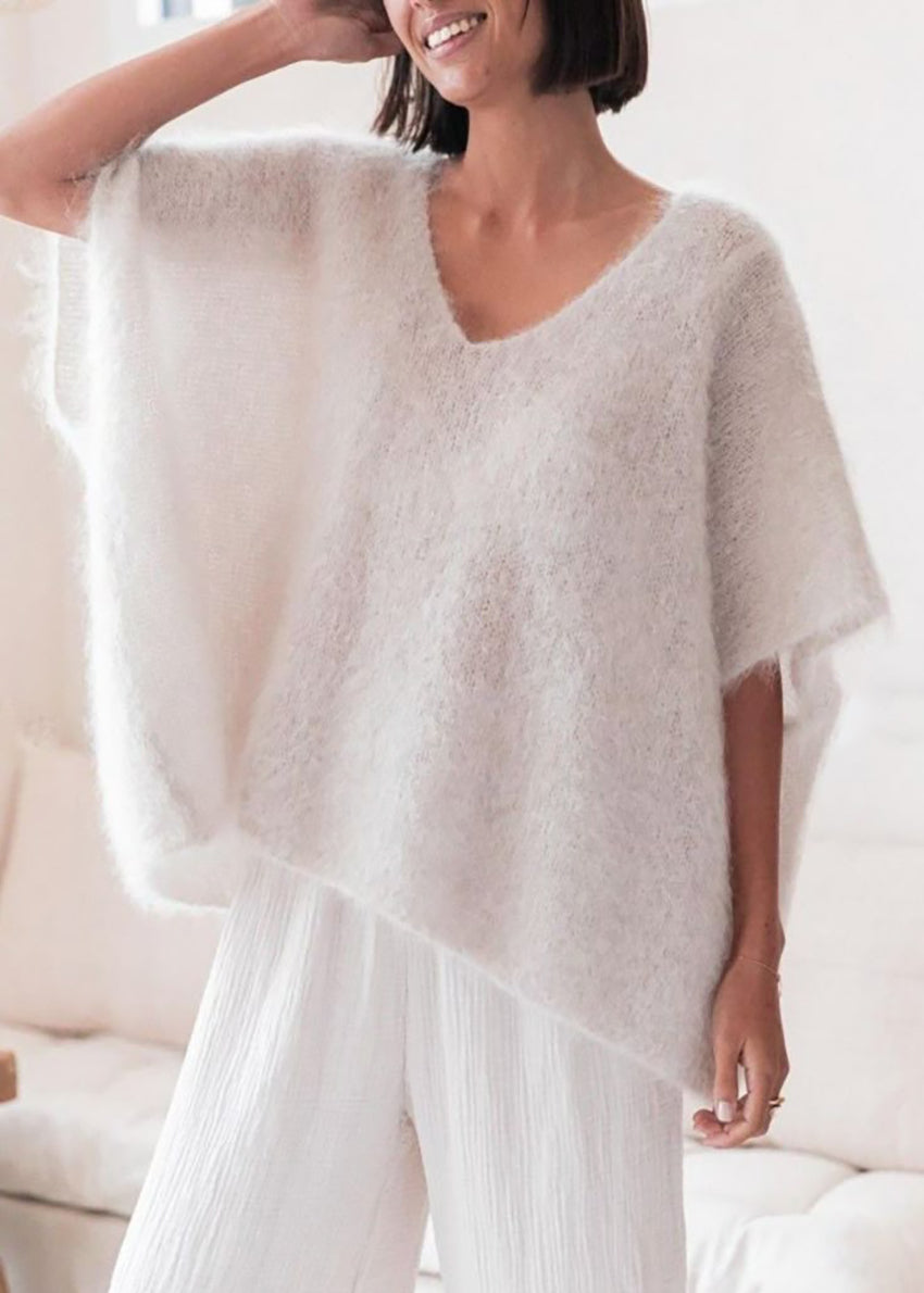 Woman wearing a white poncho in a bright room