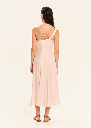 Woman wearing a light pink slip dress on a white background