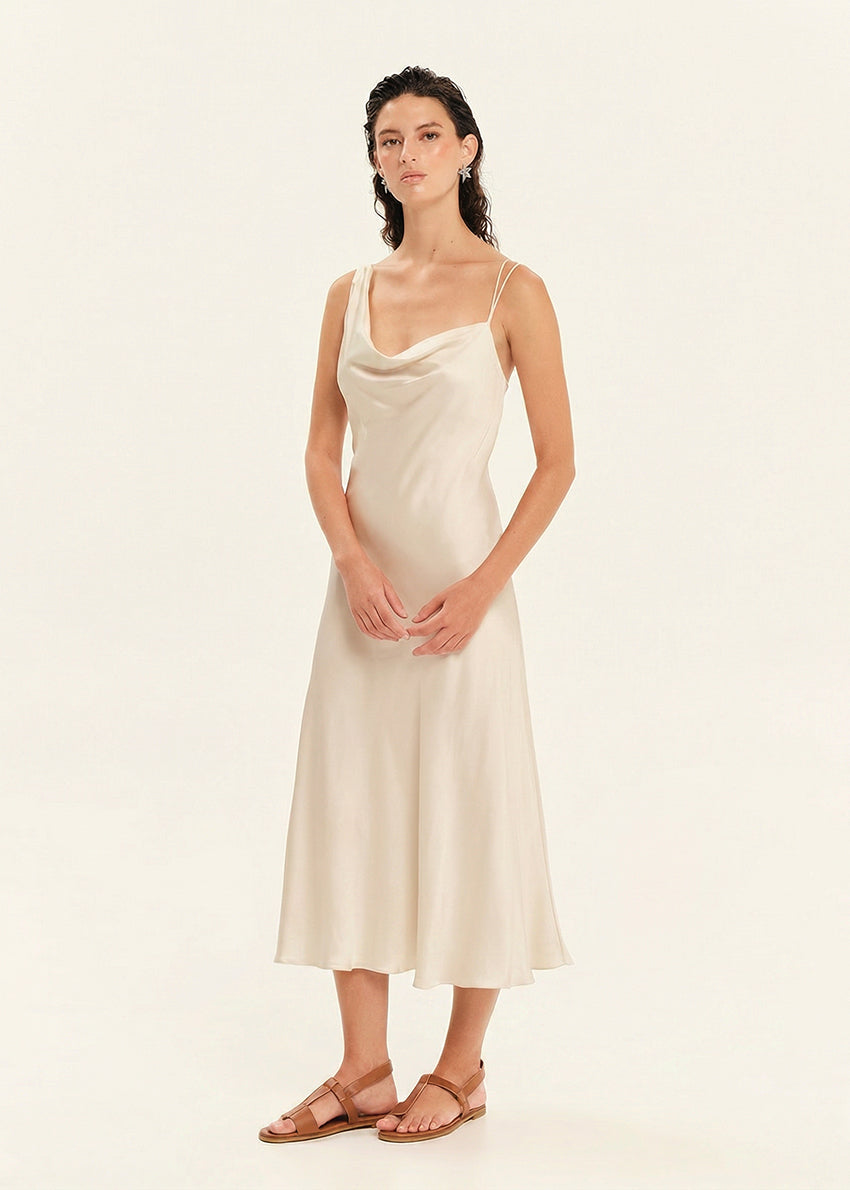 Woman wearing a beige slip dress against a plain background
