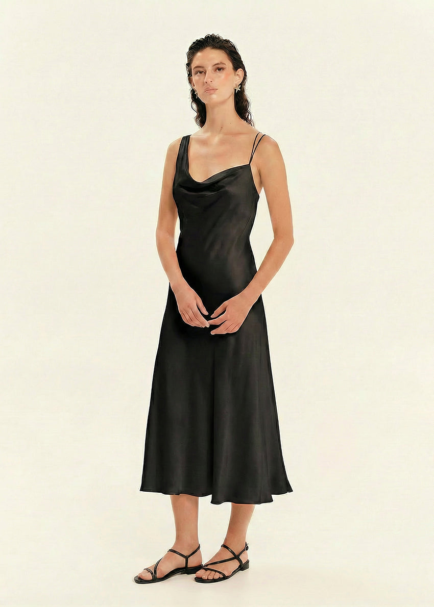 Woman wearing a black slip dress on a beige background