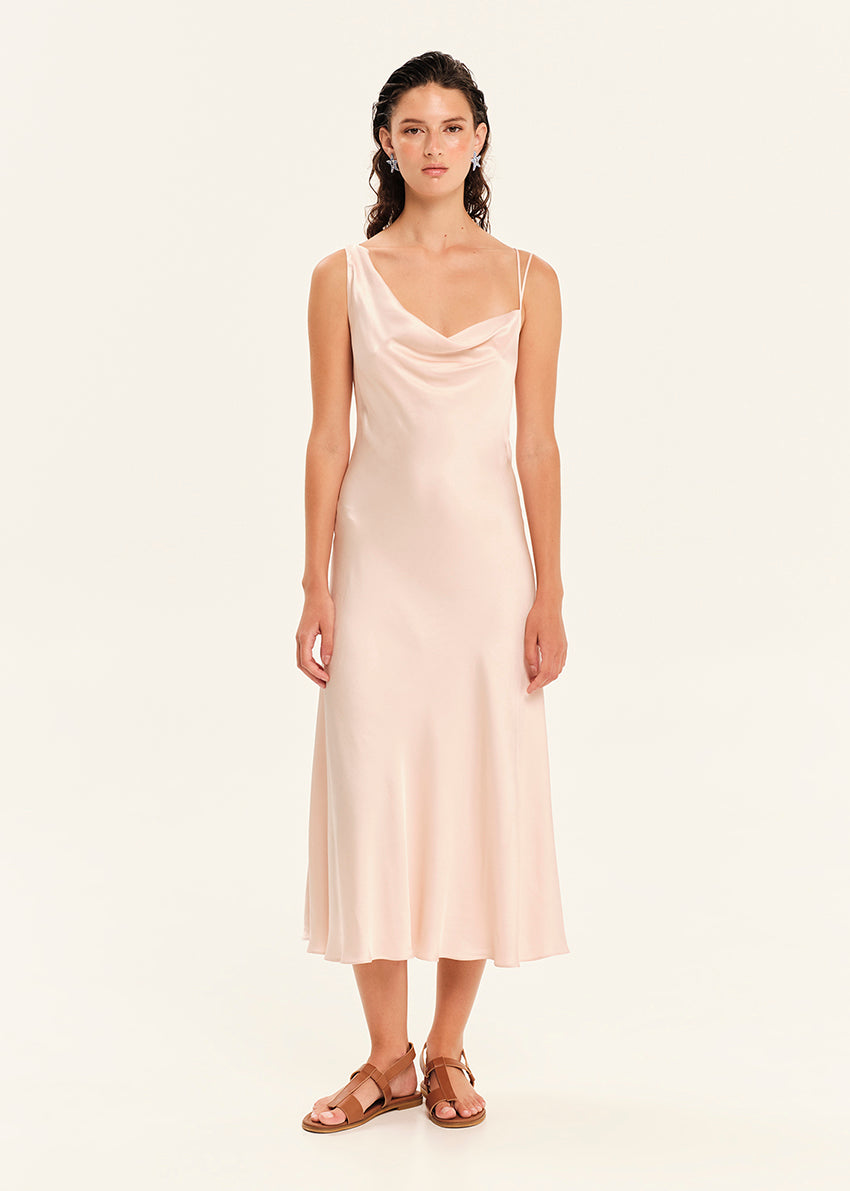 Woman wearing a light pink slip dress on a white background