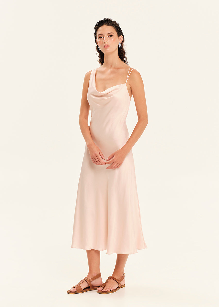 Woman wearing a light pink slip dress on a white background