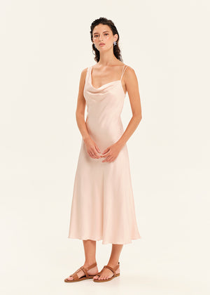 Woman wearing a light pink slip dress on a white background