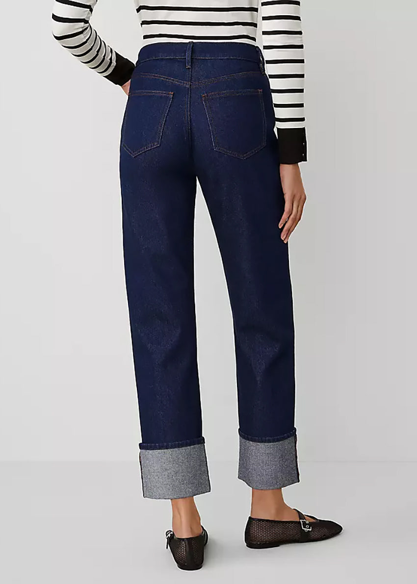 Person wearing dark blue jeans with sparkly  cuffs on a white background