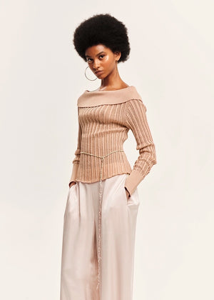 Woman wearing a beige blouse and white pants on a light background