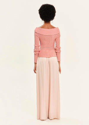 Woman wearing a pink blouse and pink pants on a light background