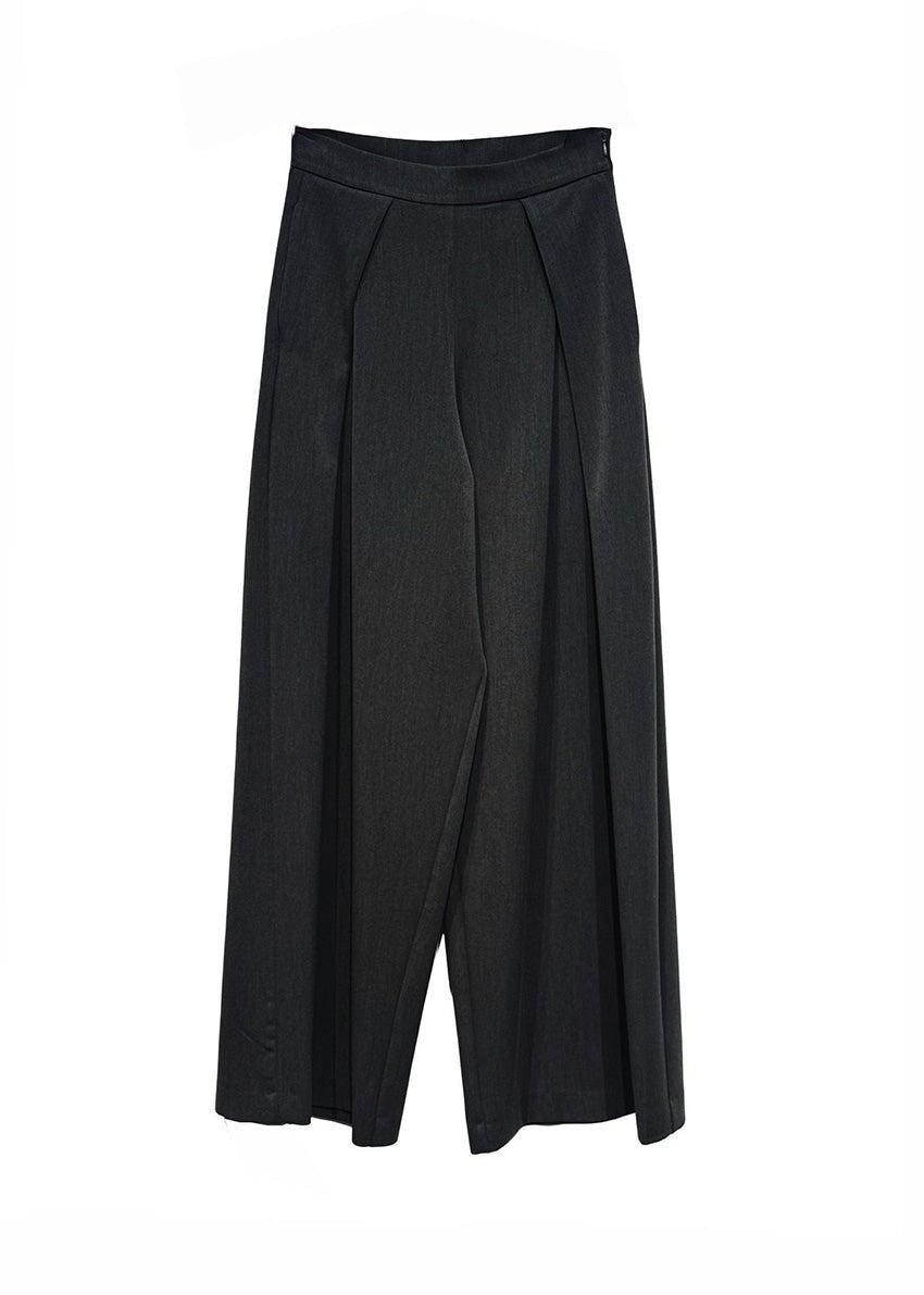 Person wearing a black outfit with wide-leg pants against a plain background