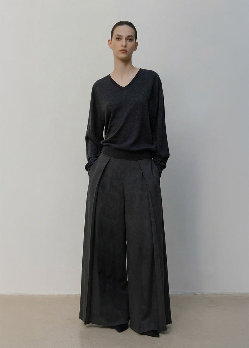 Person wearing a black outfit with wide-leg pants against a plain background