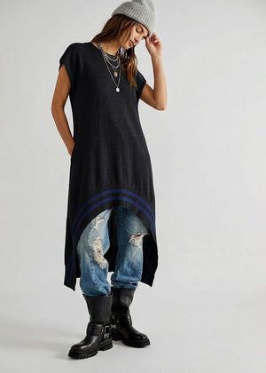 Person wearing a black sleeveless dress with a blue stripe, ripped jeans, and black boots on a white background