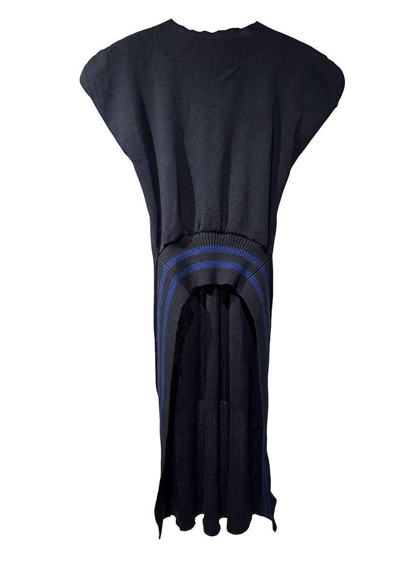 Person wearing a black sleeveless dress with a blue stripe, ripped jeans, and black boots on a white background