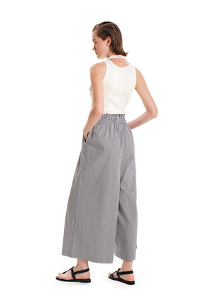 A model wearing wide leg striped pants with a rouched waist and a beige top.