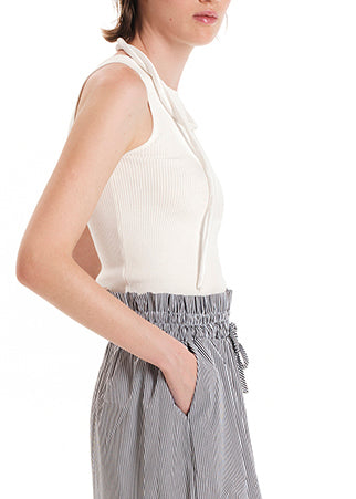A model wearing wide leg striped pants with a rouched waist and a long beige top.