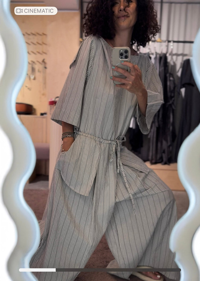 Person wearing a gray striped outfit taking a mirror selfie.