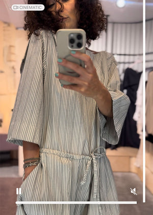 Person taking a mirror selfie wearing a striped dress in a store setting.