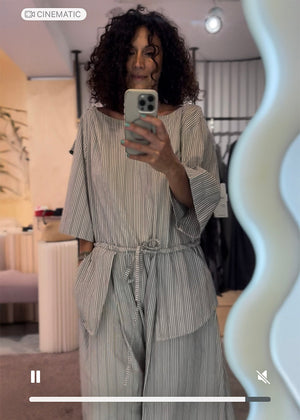 Woman taking a mirror selfie wearing a striped outfit in a store.