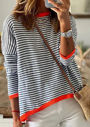A person wearing a striped crop top with a wide boat neckline and cropped cut, paired with white pants, accessorized with a bag and a watch.