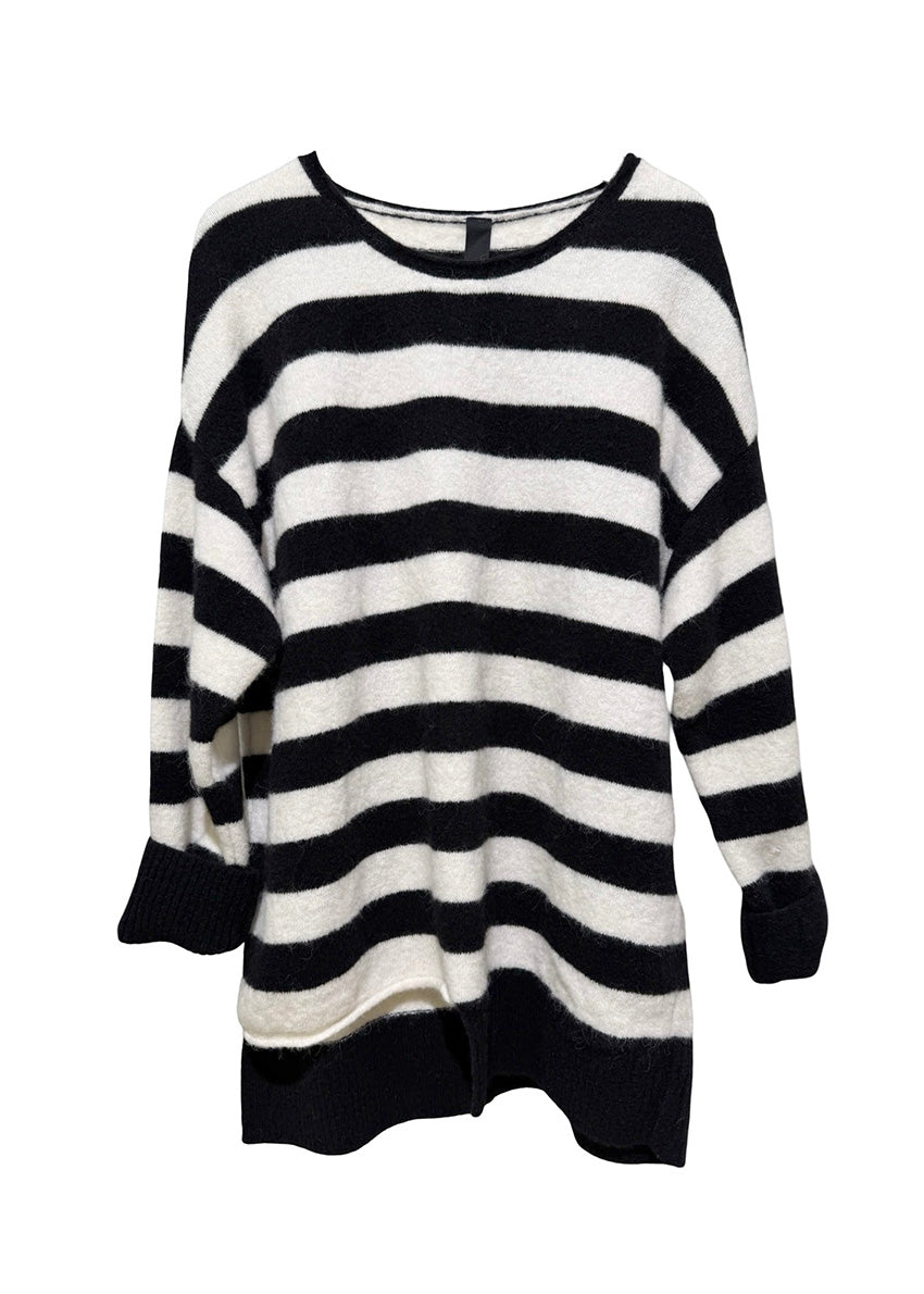 Person wearing a black and white striped sweater sitting on a white surface.