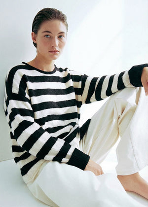 Person wearing a black and white striped sweater sitting on a white surface.