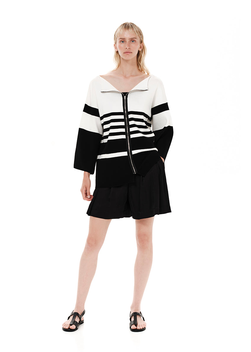 A striped cardigan with color block design in white and black, featuring a front zipper closure and bell sleeves.