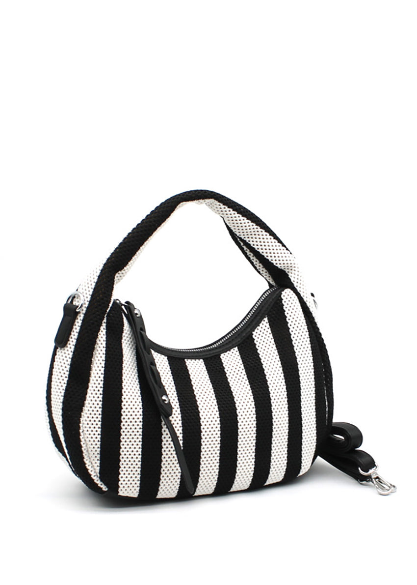 A handbag with a bold black and white striped design, featuring a crescent shape and a detachable strap.