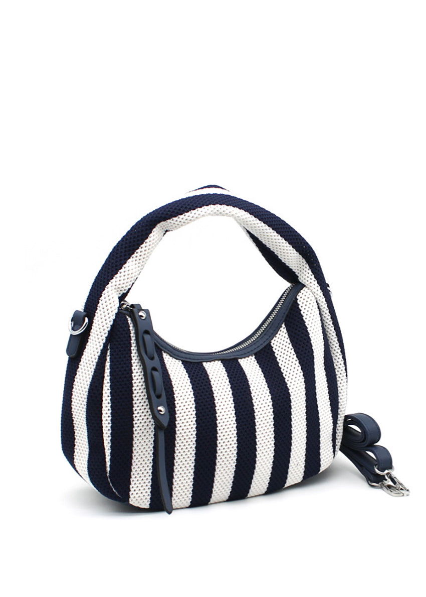 A handbag with a bold black and white striped design, featuring a crescent shape and a detachable strap.