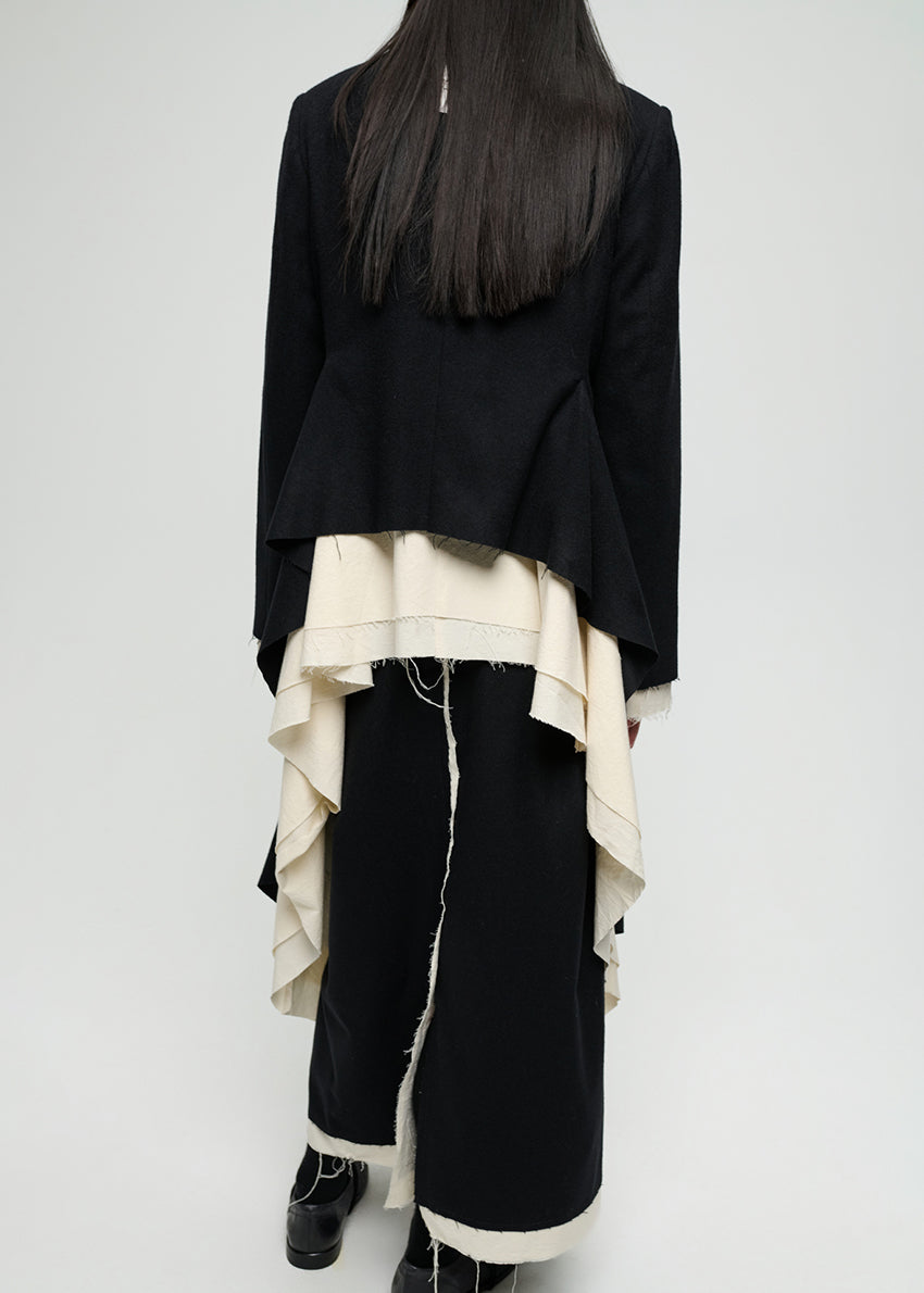 Person wearing a black outfit with white accents on a plain background