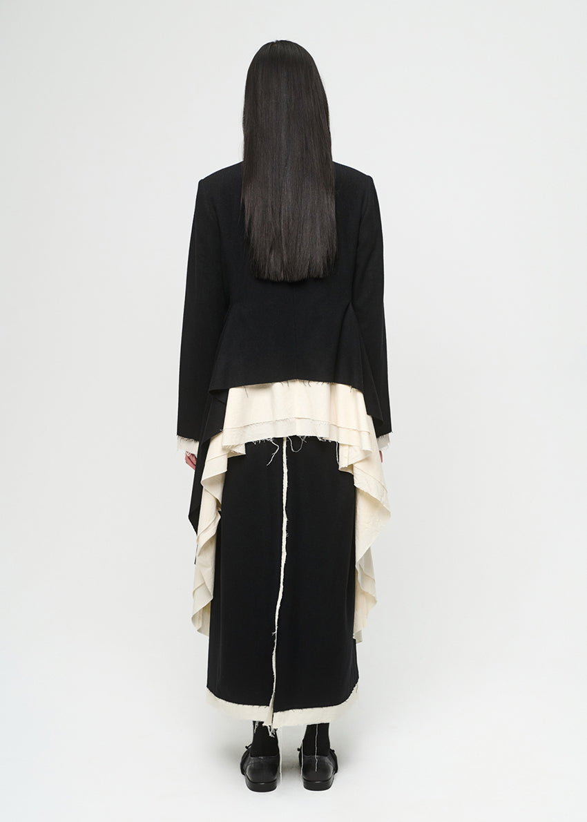 Person wearing a black outfit with a white layered coat on a white background