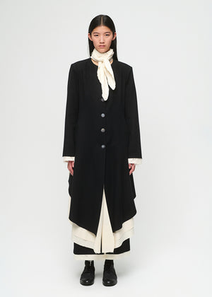 Person wearing a long black coat with a white scarf on a white background