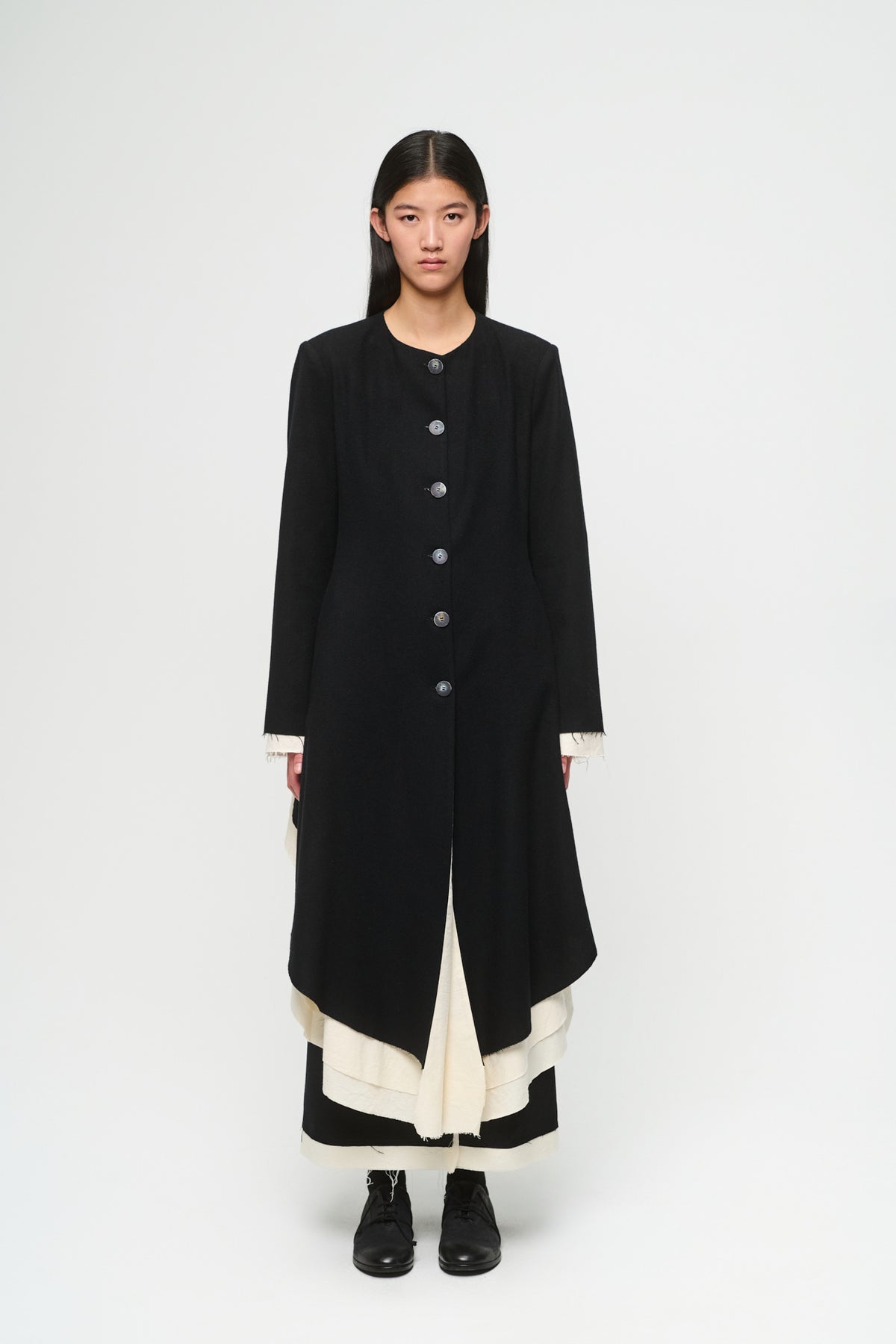 Person wearing a long black coat on a white background