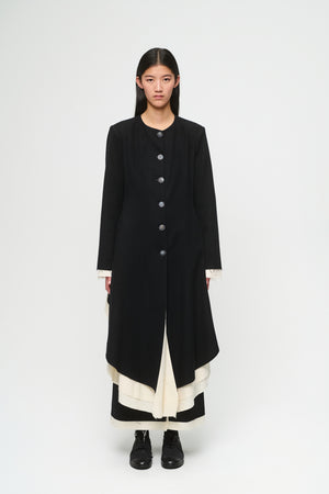 Person wearing a long black coat on a white background