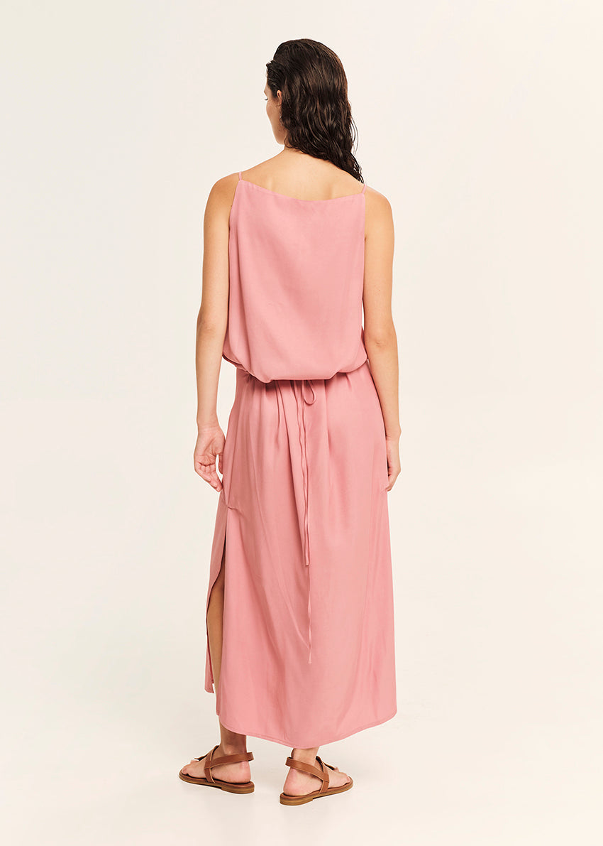 Woman wearing a straight-cut maxi dress with discret key hole at the bust and delicate pleats along the side seams, white side ties allow to create a new silhouette that drapes around the waist.