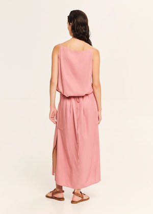 Woman wearing a straight-cut maxi dress with discret key hole at the bust and delicate pleats along the side seams, white side ties allow to create a new silhouette that drapes around the waist.