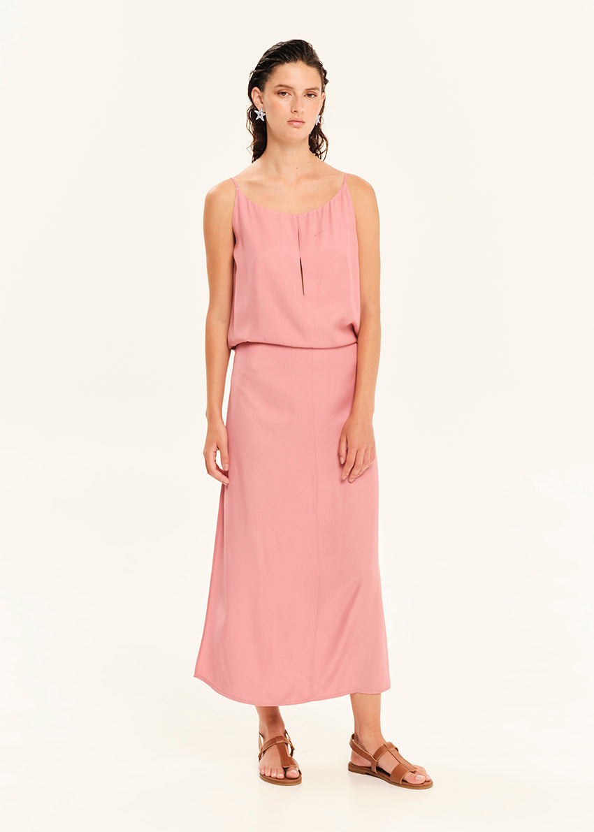 Woman wearing a straight-cut maxi dress with discret key hole at the bust and delicate pleats along the side seams, white side ties allow to create a new silhouette that drapes around the waist.