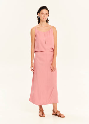 Woman wearing a straight-cut maxi dress with discret key hole at the bust and delicate pleats along the side seams, white side ties allow to create a new silhouette that drapes around the waist.