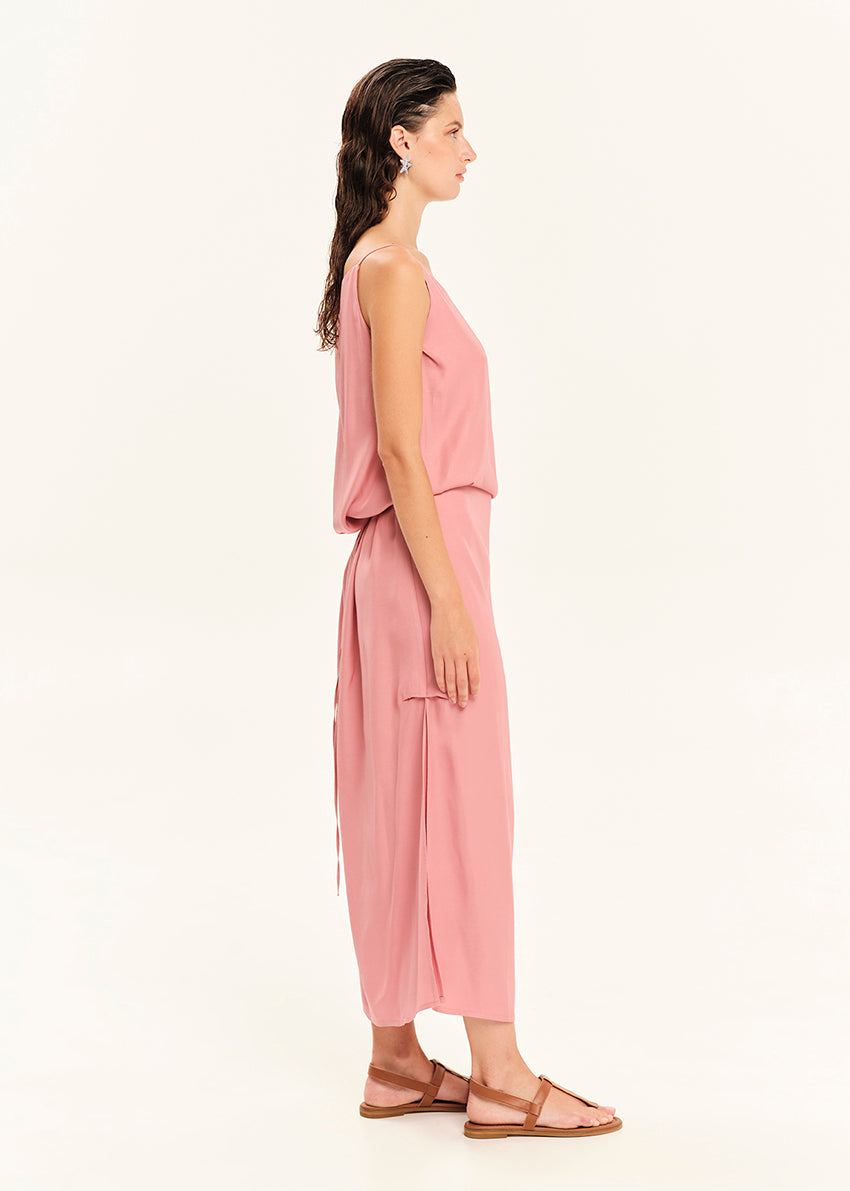 Woman wearing a straight-cut maxi dress with discret key hole at the bust and delicate pleats along the side seams, white side ties allow to create a new silhouette that drapes around the waist.