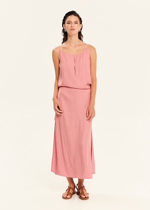 Woman wearing a straight-cut maxi dress with discret key hole at the bust and delicate pleats along the side seams, white side ties allow to create a new silhouette that drapes around the waist.