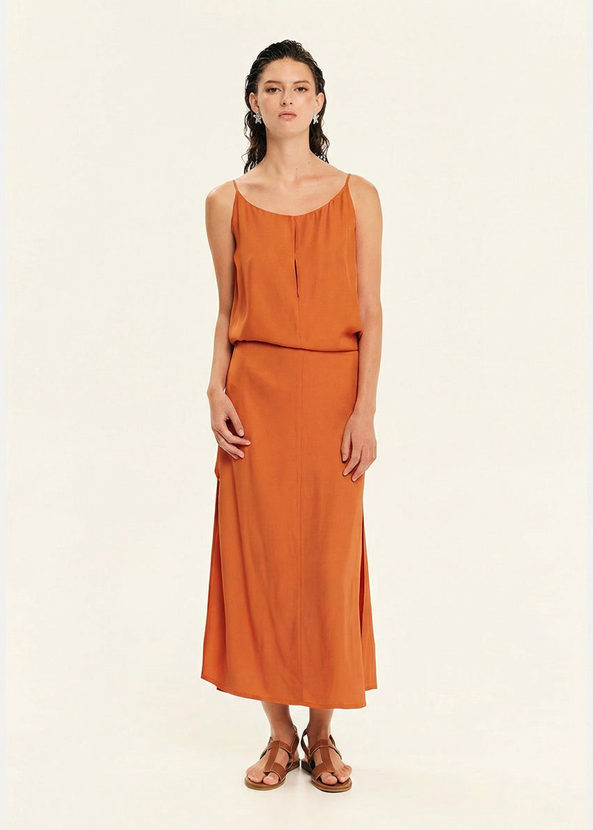 Woman wearing a straight-cut maxi dress with discret key hole at the bust and delicate pleats along the side seams, white side ties allow to create a new silhouette that drapes around the waist.