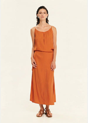 Woman wearing a straight-cut maxi dress with discret key hole at the bust and delicate pleats along the side seams, white side ties allow to create a new silhouette that drapes around the waist.