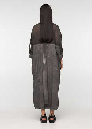 A person standing wearing a long, loose-fitting, grey shirt with 3/4-length sleeves, a collar, and buttons down the front. The shirt features a decorative vertical belt at the back and two side pockets.