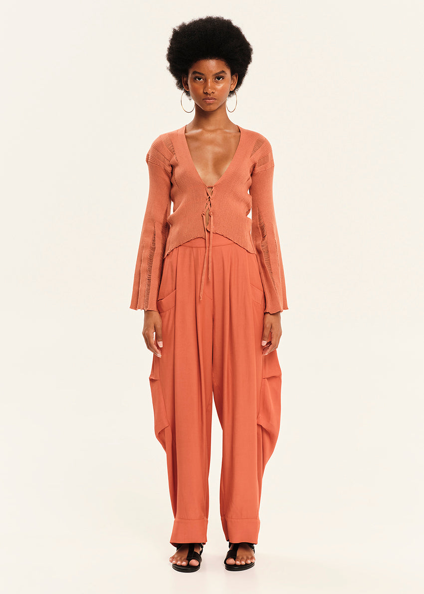 Woman wearing a peach-colored outfit with a matching cardigan on a white background