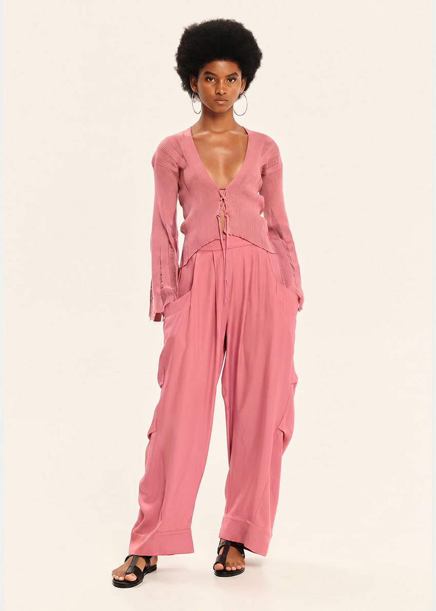 Woman wearing a pink cardigan with pink pants on a white background