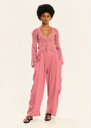 Woman wearing a pink cardigan with pink pants on a white background