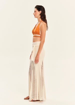 Woman wearing a mustard yellow top and beige skirt on a white background