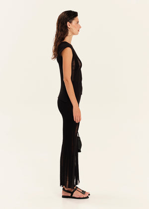 Woman wearing a black sleeveless top and black pants with sheer panels on a white background