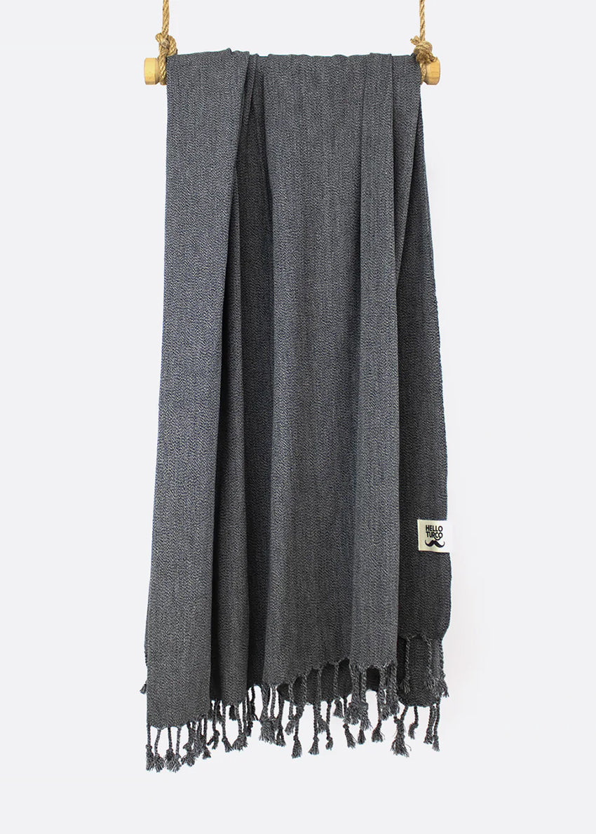 A gray, thin, tight-knitted towel with fringes hanging at the bottom, made of luxury Turkish cotton, displayed on a white background.