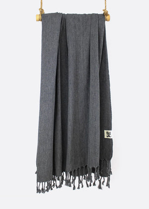 A gray, thin, tight-knitted towel with fringes hanging at the bottom, made of luxury Turkish cotton, displayed on a white background.