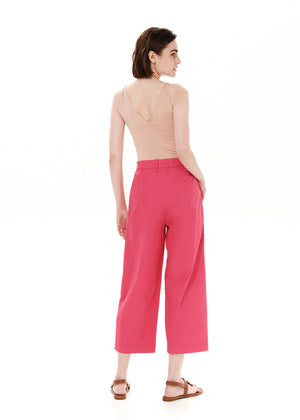 Person wearing a beige tank top with pink pants from the back on a white background 