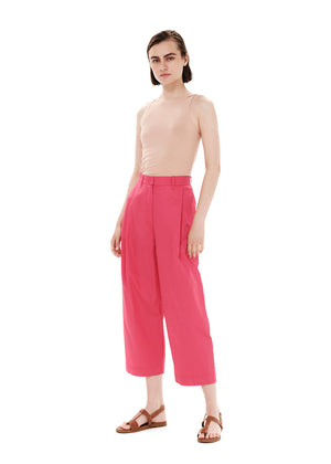 Person wearing a beige tank top with pink trousers on a white background 