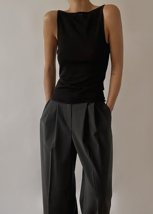 A person wearing a black sleeveless tank top with a V-shaped back and matching grey trousers.